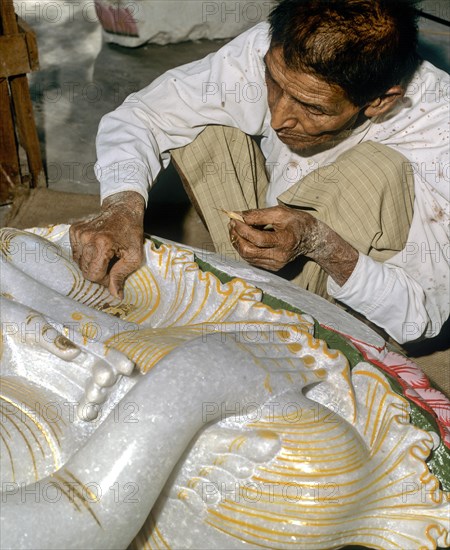 Man gilding a marble Buddha statue