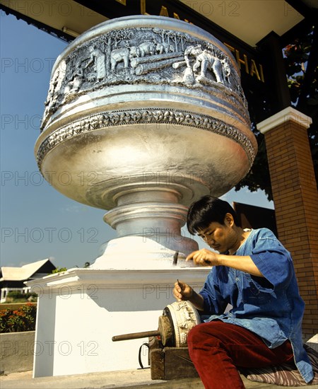 Worker in a silver factory peening a bowl