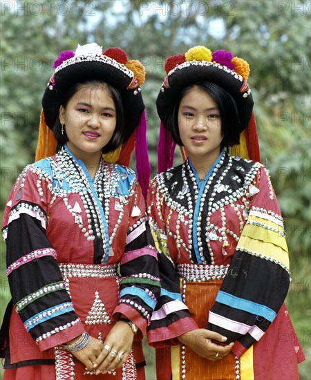 Two Lisu girls wearing colourful headdresses and the traditional costume of the mountain people