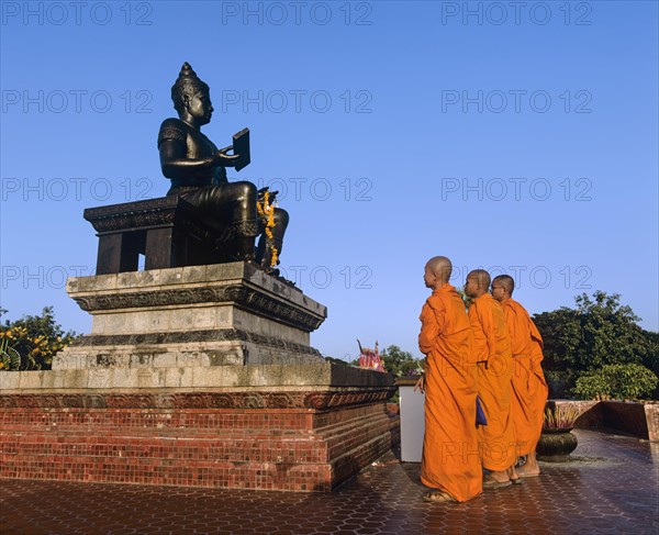 Buddhist monks standing in front of the monument of King Ramkhamhaeng
