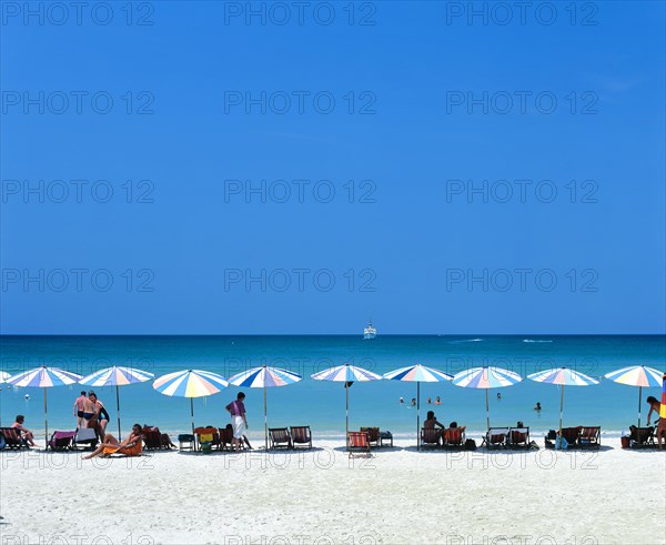 Tourists on Patong Beach with sunshades and beach chairs