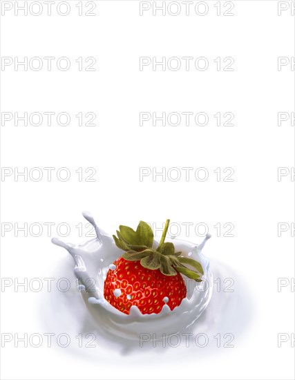 Strawberry falling into milk