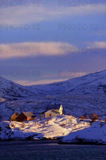 Fishing village beside a fjord with wintry mountains