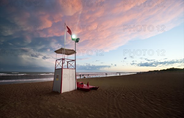 Observation tower on the sea with moody clouds and the afterglow of sunset