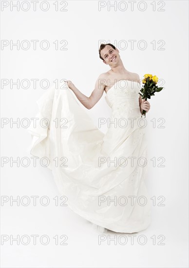 Man wearing a wedding dress and holding a bridal bouquet