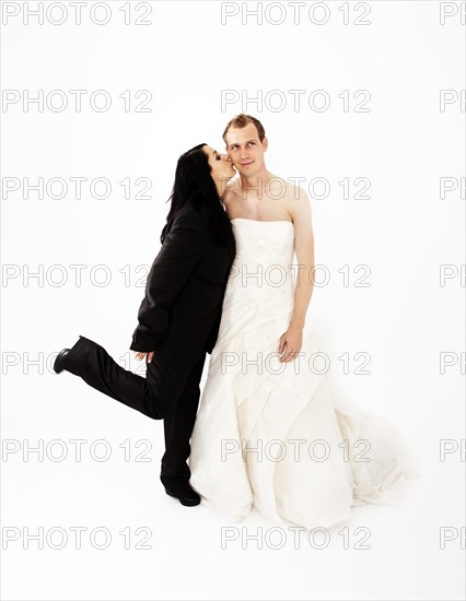 Bride wearing a suit kissing a groom wearing a wedding dress on the cheek