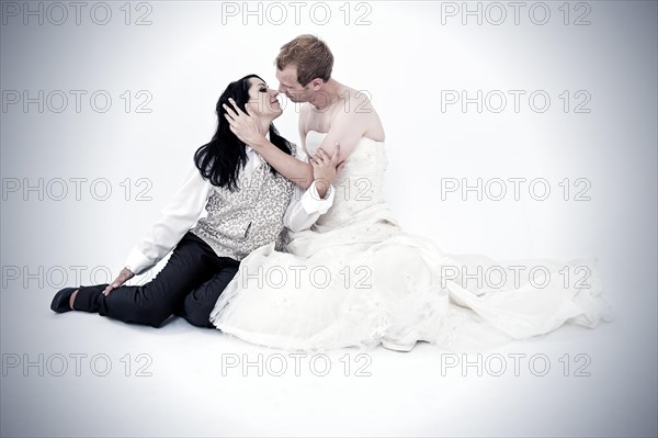 Bride wearing a suit kissing a groom wearing a wedding dress