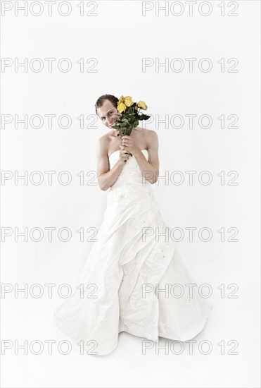 Man wearing a wedding dress and holding a bridal bouquet