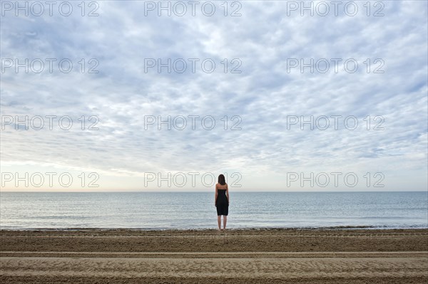 Woman wearing a black dress standing by the sea