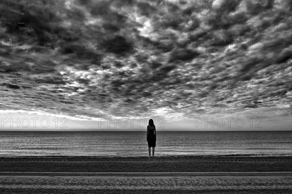 Woman wearing a black dress standing by the sea