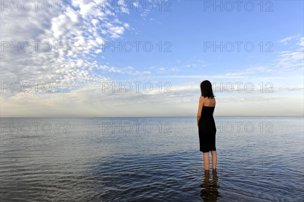 Woman wearing a black dress standing in the water of the sea