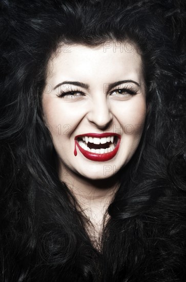 Young Woman dressed as a vampire with blood on her red lips