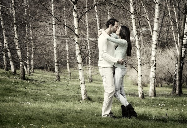 Young couple kissing in a birch forest