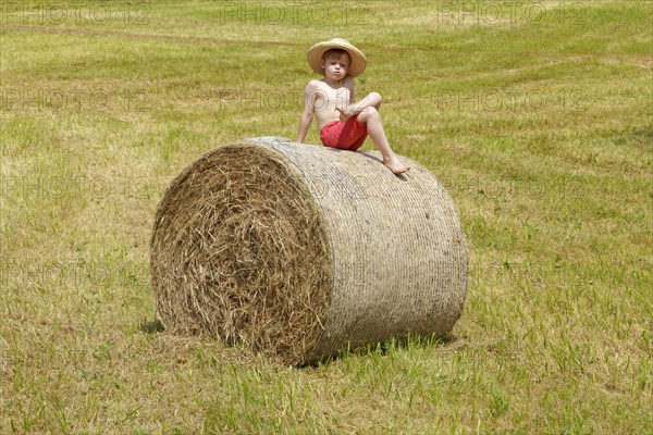 Boy sitting on a bale of straw