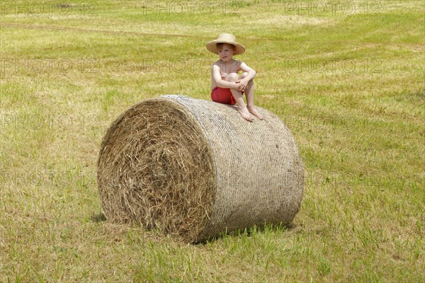 Boy sitting on a bale of straw