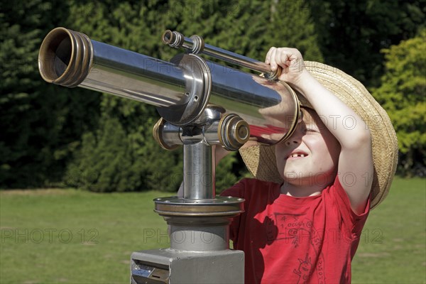 Young boy looking through a telescope