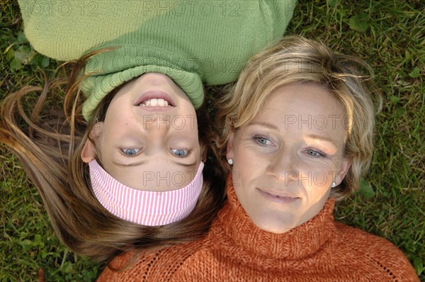 Mother and daughter lying head to head on the grass