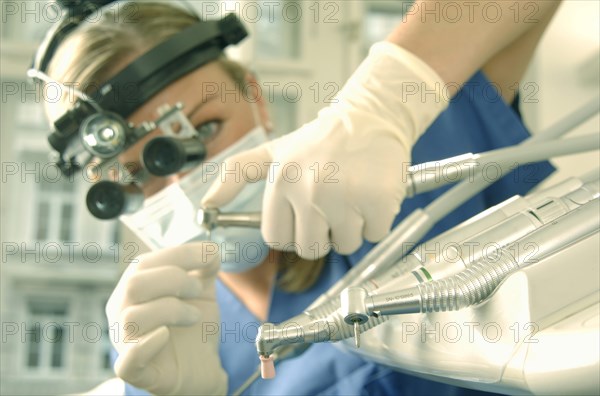 Dentist wearing magnifying loupes preparing a drill