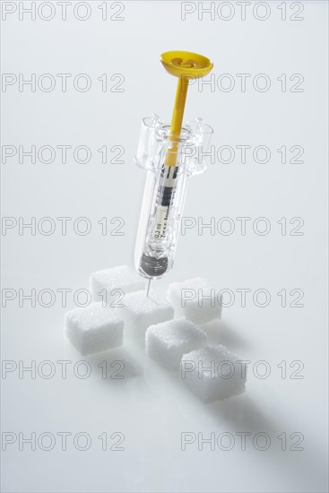 Sugar cubes in a cross-shape with a syringe filled with insulin