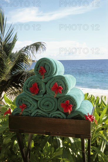 Stack of rolled towels with red flower on the beach