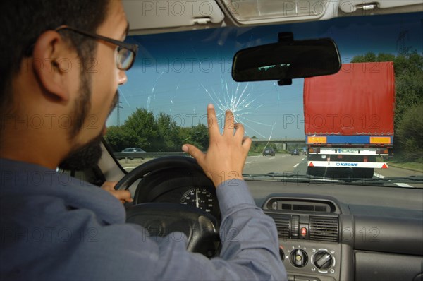 Shocked motorist reacting after a rock has hit the windscreen of his car