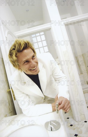 Man wearing a white suit snorting cocaine with a rolled bill