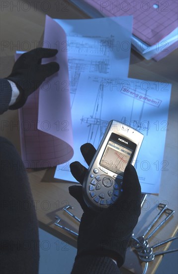 Burglar using a camera phone to take a photograph of secret plans