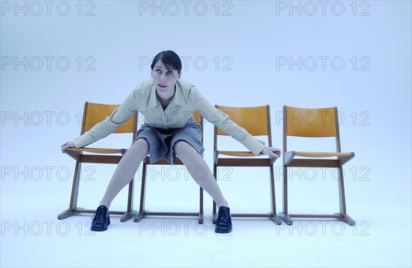 Woman wearing conservative clothes sitting on a chair and saving the places on the chairs beside her