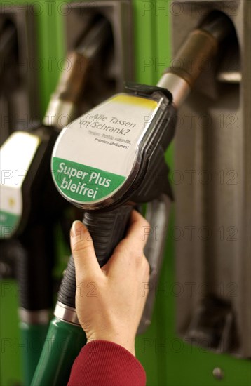 Woman's hand holding a fuel pump nozzle with Super Plus bleifrei