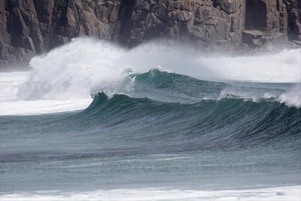 Waves with spray in front of a cliff