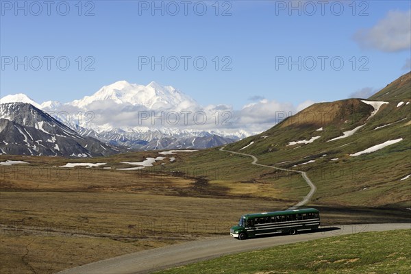 A shuttle bus crossing the Denali National Park and Preserve with views of Mt McKinley at back