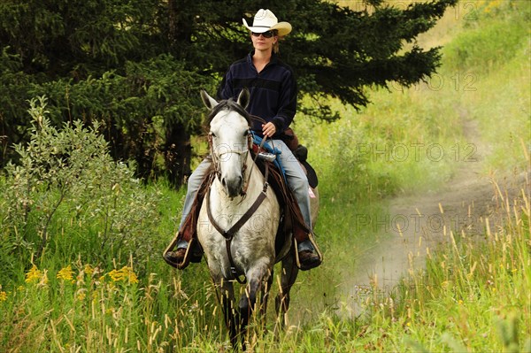 Cowgirl riding a gray horse