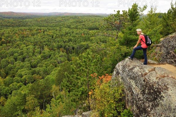 Female hiker standing on a rock overlooking woodlands