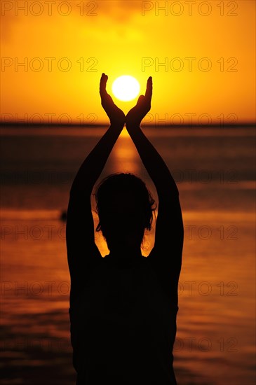 Woman holding the sun with both her hands