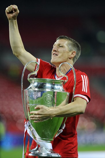 Bastian Schweinsteiger cheering jubilantly while holding the trophy