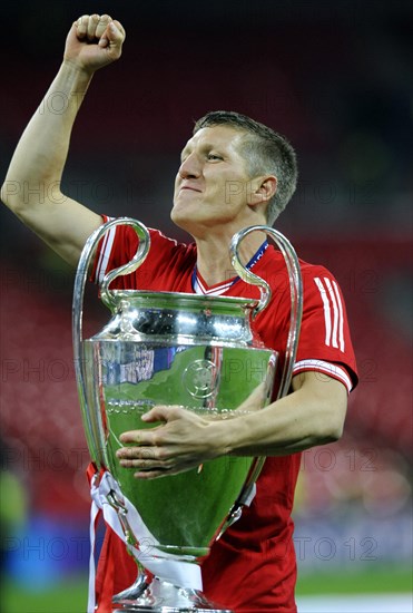 Bastian Schweinsteiger cheering jubilantly while holding the trophy