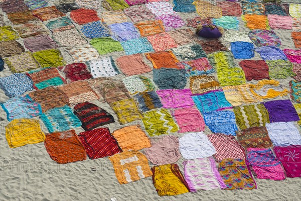 Colourful saris laying to dry after washing on a sandbank on the banks of the Yamuna River