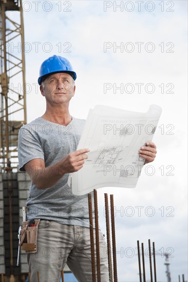 Construction worker wearing a hard hat and holding a building plan