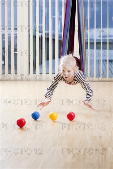 Girl during a coordination exercise with small balls while swinging in a hammock
