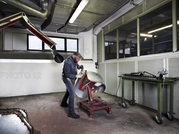 Worker grinding a fender in a workshop