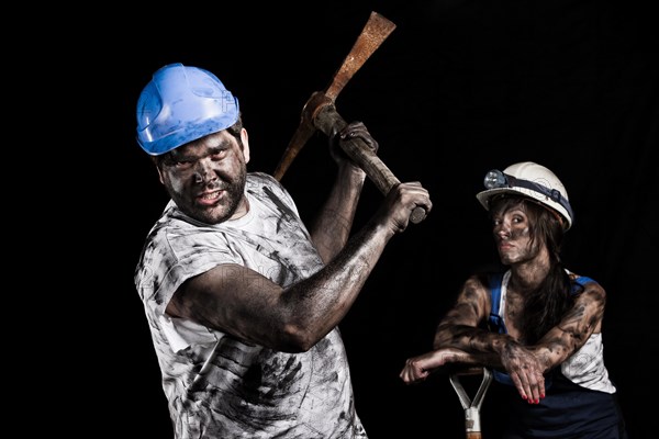 Miner holding a pick with a female miner behind him