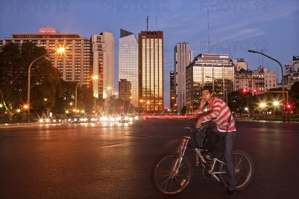 Young man sitting on his bike waiting at the crossroads of Av del Libertador - Crucero Gral Belgrano