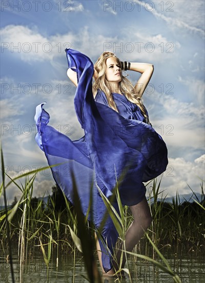 Woman wearing a blue dress standing between the reeds