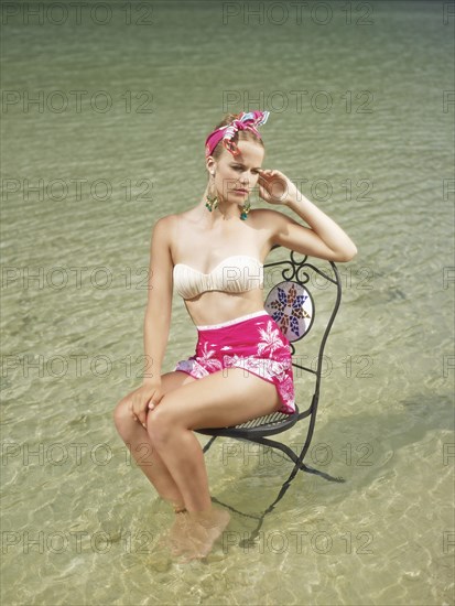 Woman sitting on a chair in the water