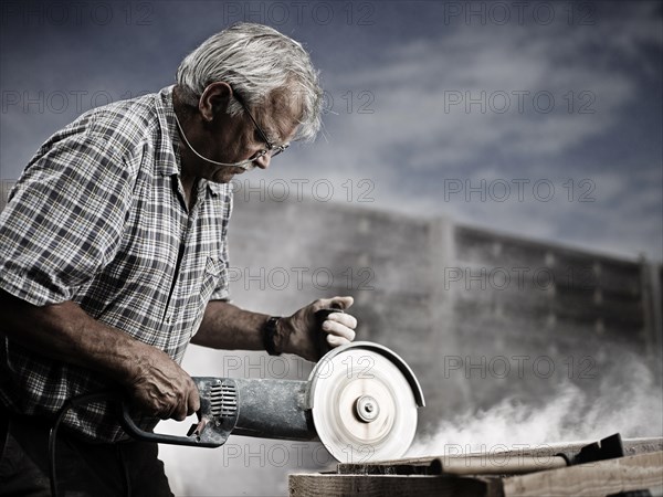 Stonemason cutting a stone slab with an angle grinder with a cutting disc