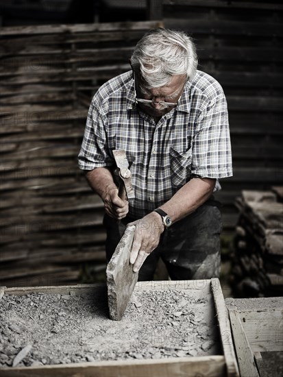 Stonemason working on a stone slab with a hammer