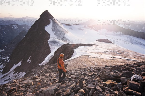 Mountain climber standing at the summit of Wilder Pfaff Mountain and looking towards the sunset