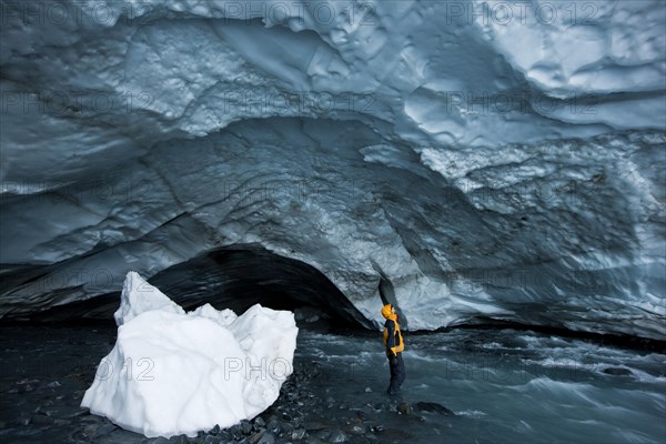 Mountaineer looking up at the ceiling of an ice cave