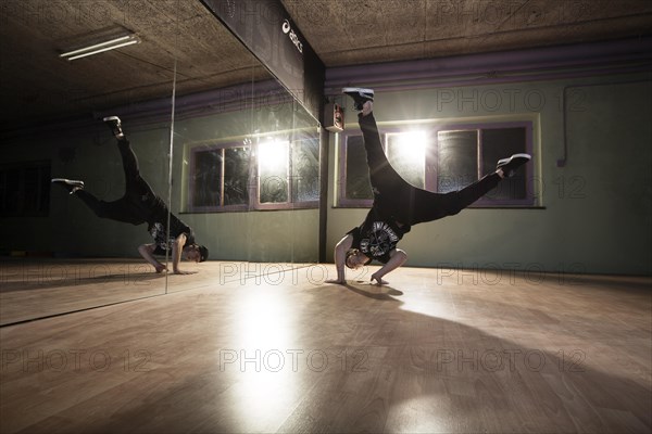 Breakdancer dancing in front of a mirror wall