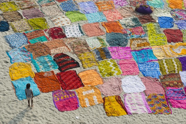 Colourful saris laying to dry after washing on a sandbank on the banks of the Yamuna River